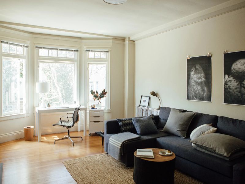 A clean and comfortable living room with lights coming through the window.