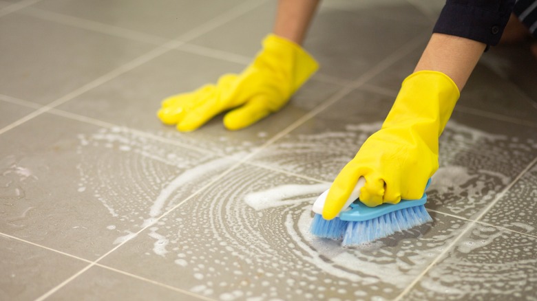 cleaner scrubbing bathroom tiles and shower during deep cleaning